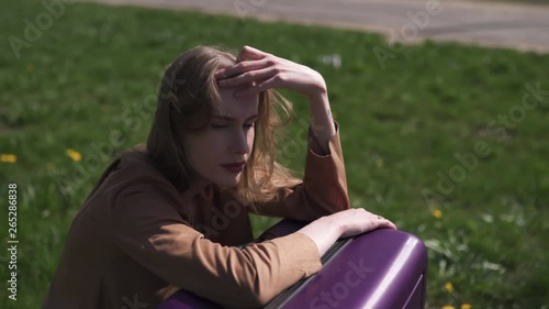 Sad traveler missed her flight and bus - Sitting on her luggage suitcase and crying - Emotions of a white caucasian female woman with light long hair wearng bra and beige jacket photo