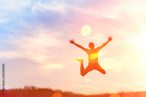 Happy man jumping at top of mountain with sunset sky abstract background.