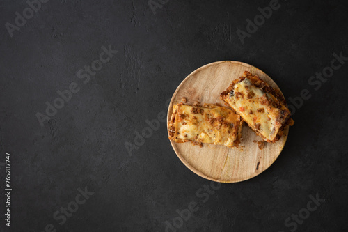 Tasty lasagne with meat, cheese on wooden plate, top view