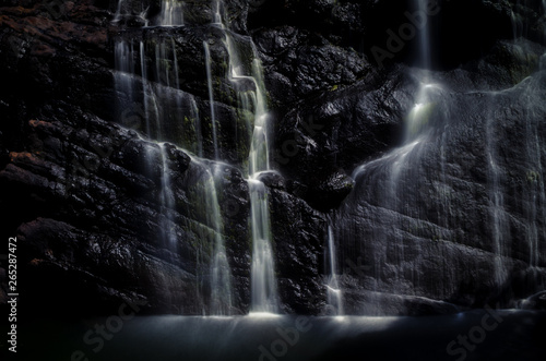 Multiple waterfall streams with silk effect on black stone. photo
