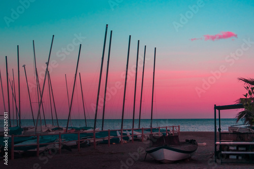 Barcos varados y un chiringuito en la playa durante el atardecer rosa photo