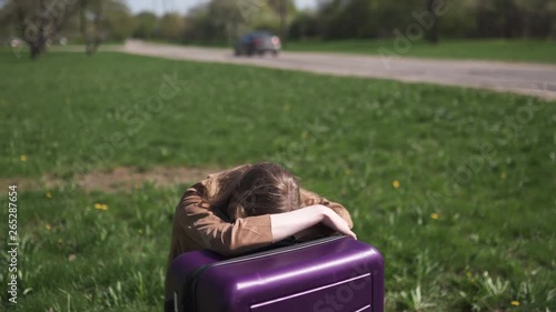 Sad traveler missed her flight and bus - Sitting on her luggage suitcase and crying - Emotions of a white caucasian female woman with light long hair wearng bra and beige jacket