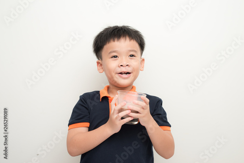 Young boy drinking chocolate milk isolated on white wall background.
