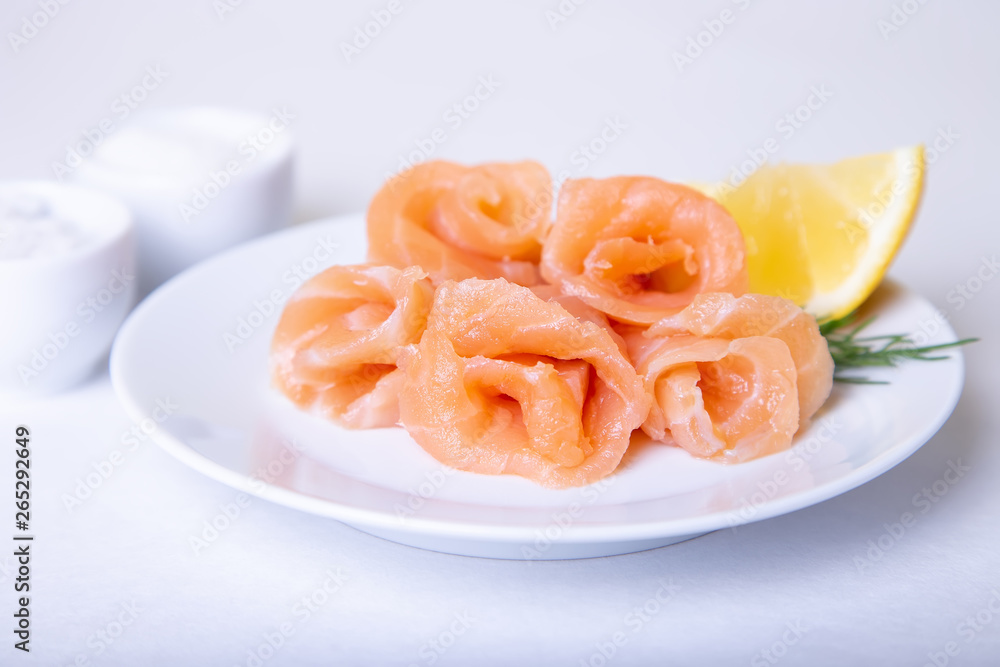 Salted salmon on a white plate with lemon and dill. White background, selective focus, close-up.