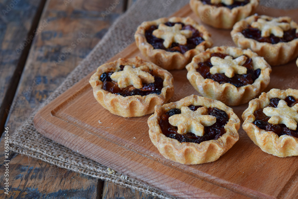 Mini Tartlets with dried fruits and nuts. Shortbread cookies with fruits stuffing on wooden background. Small sweet pie. Copy Space.