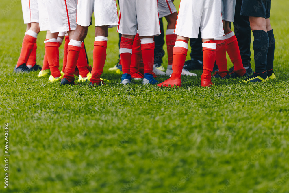 Obraz premium Junior Soccer Team Standing in Group. Football Grass Field and Players Feet. Soccer Stadium Grass Background. Soccer Field at School. Young Soccer Players Training on Pitch.