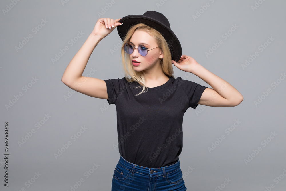 Young blonde woman in black hat and sunglasses isolated on gray background Young blonde woman in black hat and sunglasses isolated on gray background