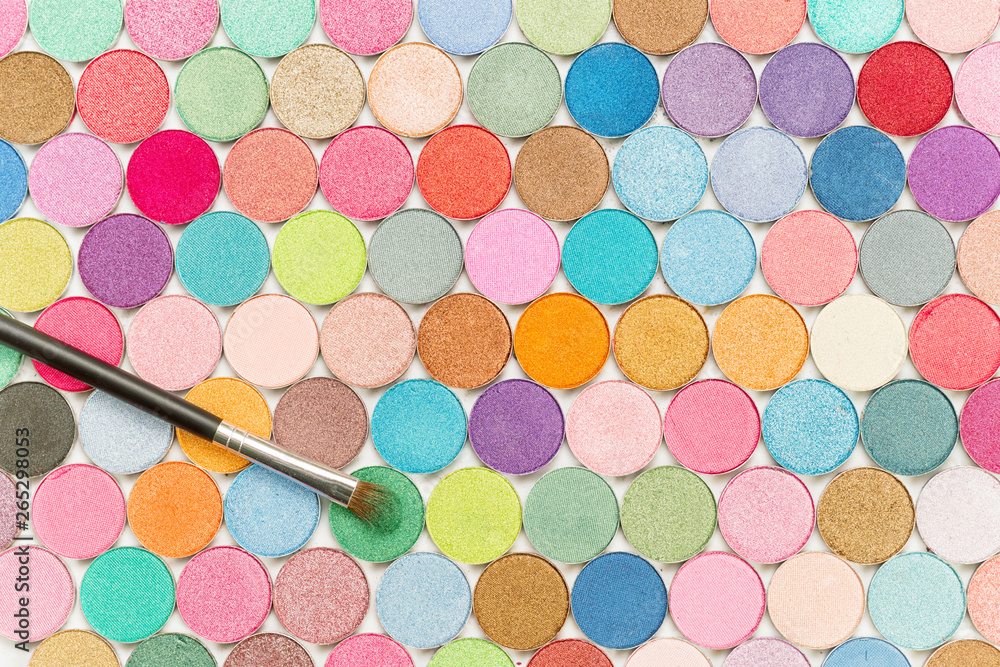 Cosmetic brushe laying on colored eye shadows top view