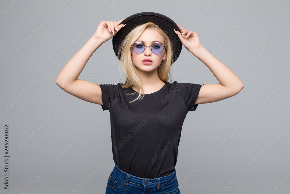 Fashion portrait pretty sweet young woman wearing a black hat sunglasses over grey background Fashion portrait pretty sweet young woman wearing a black hat sunglasses over grey background