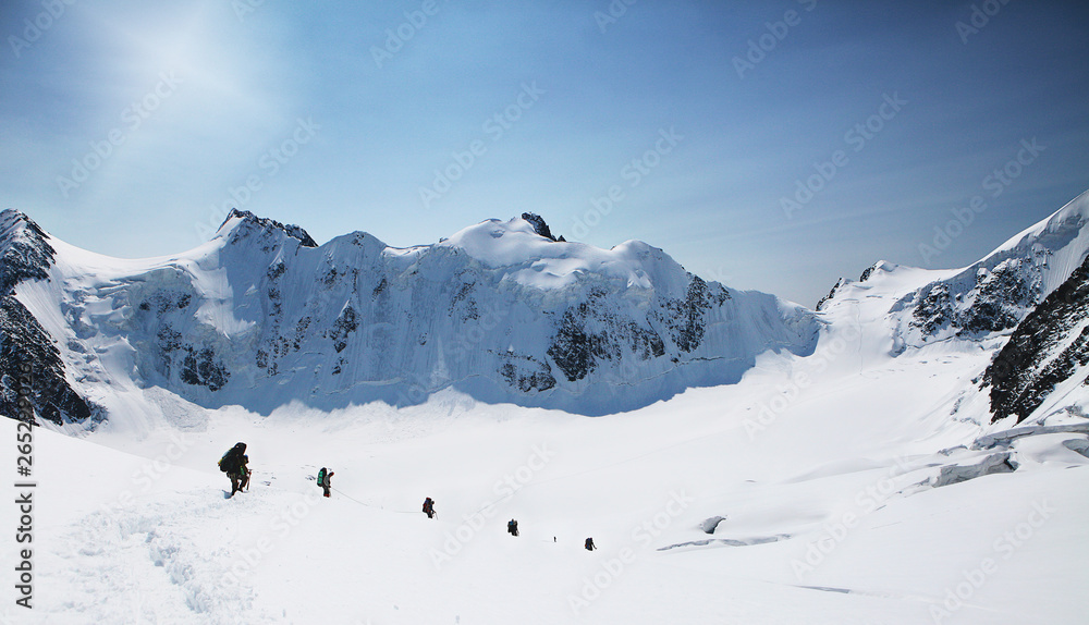 A group of mountaineers climbs to the top of a snow-capped mountain. Climbers are hiking on mountain peaks ridge. , Beautiful mountaineering tourism trekking. Concept of Motivation, Teamwork