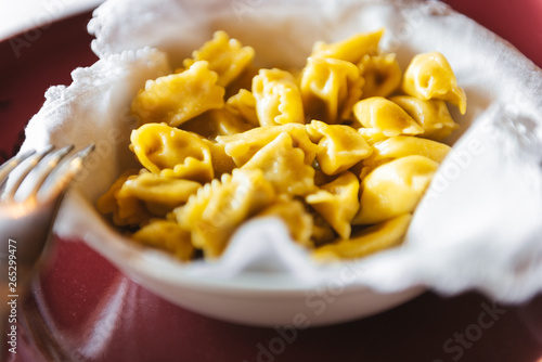 Homemade Italian ravioli in a white soup plate on a red plate