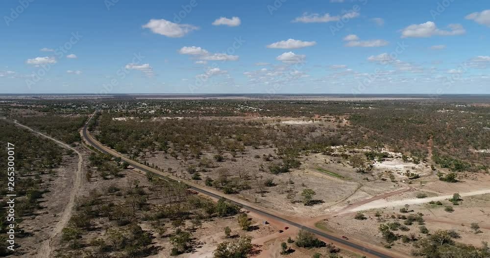 Flat arid plains of Australian outback with red soil around Lightning Ridge opal mining town in elevated aerial flying over a road connecting town to highway. Flat arid plains of Australian outback with red soil around Lightning Ridge opal mining town in elevated aerial flying over a road connecting town to highway.