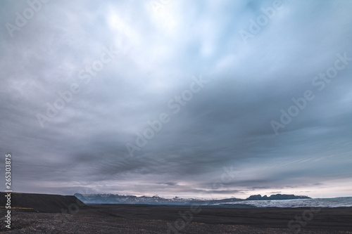Mountain landscape with river slowly floating and cloudy sky, Iceland