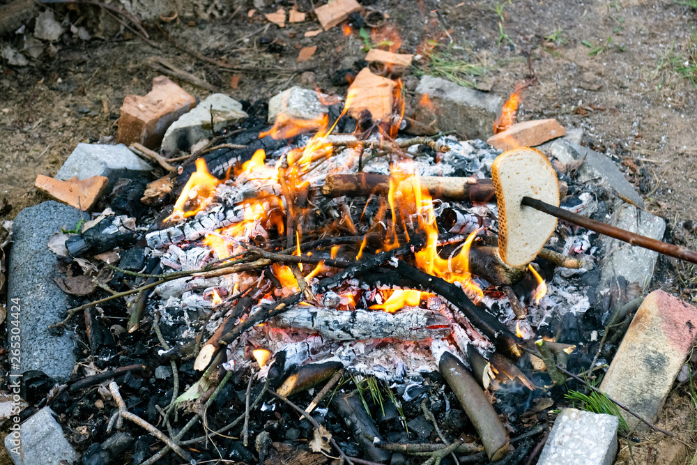Grilled slice of bread on a stick over bonfire Grilled slice of bread on a stick over bonfire