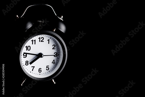 Black retro style alarm clock in the dark. Alarm clock flying in darkness.