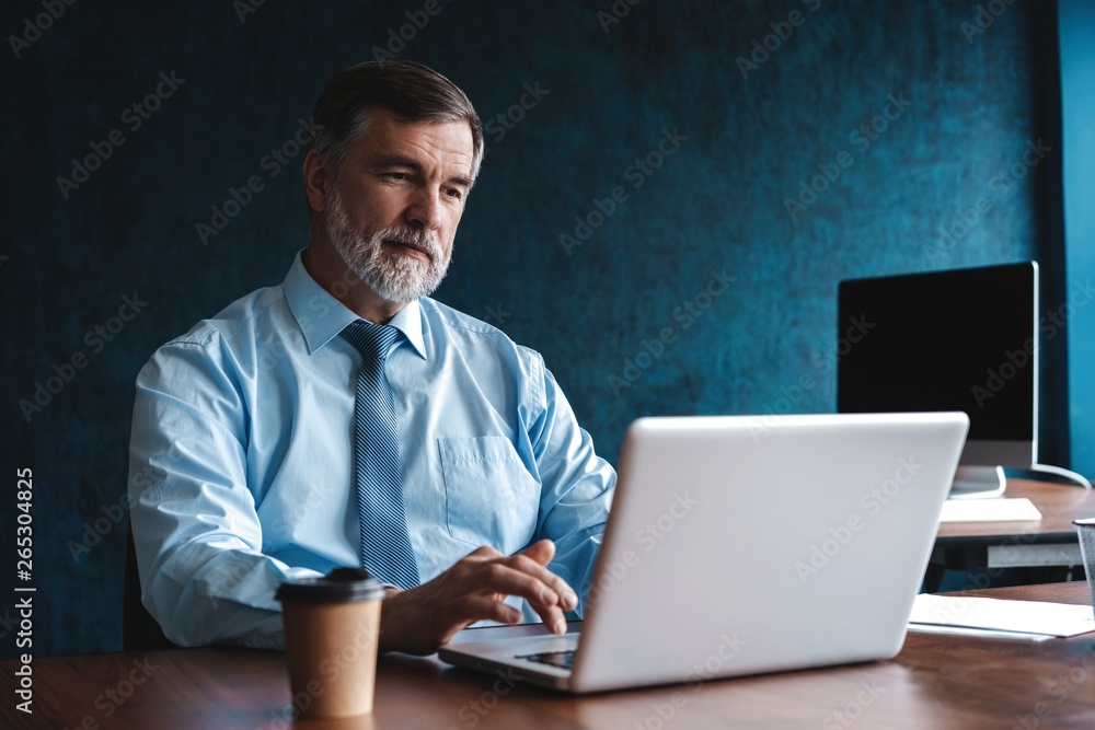Senior man in office working on laptop computer Senior man in office working on laptop computer