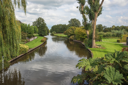 Walking over a canal bordered with gardens in Giethoorn