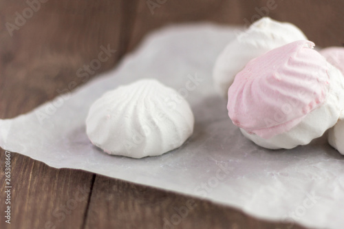 delicious dessert, delicate white and pink marshmallow on white paper on wooden background,