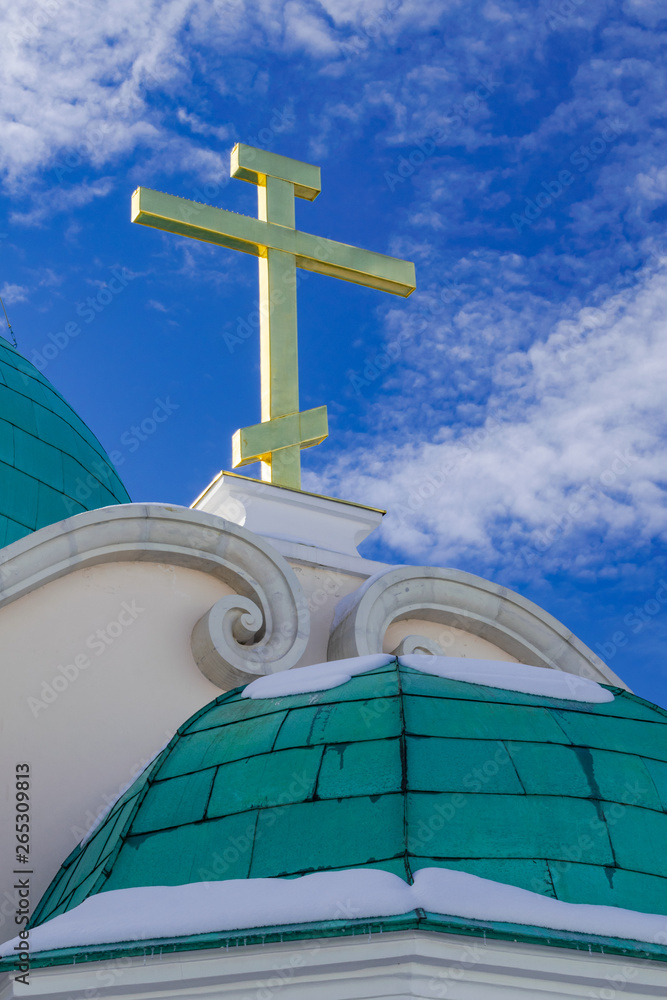 New Jerusalem orthodox monastery dome with some snow and golden cross, with sunset light, blue sky and white clouds, Istra, Russia