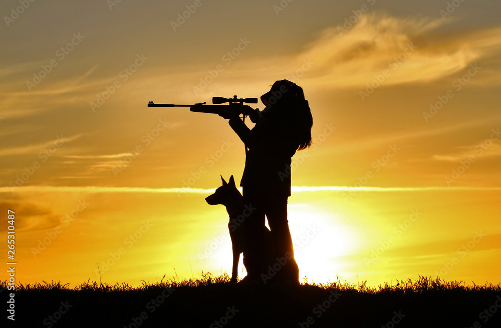 Silhouette of a girl with a rifle at sunset with a dog, a breed of Belgian Shepherd Malinois dog Silhouette of a girl with a rifle at sunset with a dog, a breed of Belgian Shepherd Malinois dog