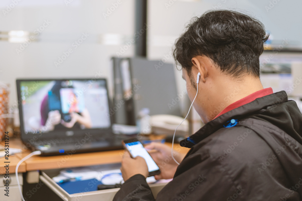business man working and play smart phone in office with soft-focus and over light in the background business man working and play smart phone in office with soft-focus and over light in the background