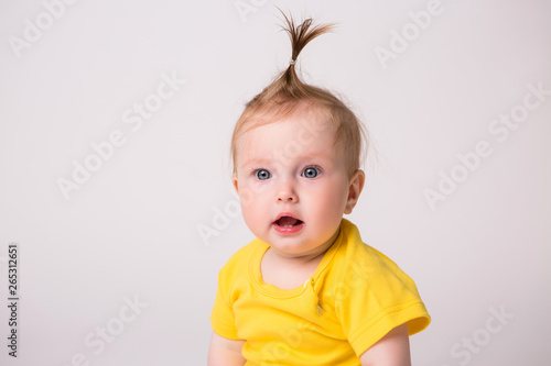 healthy baby is 6 months, baby girl smiling in a yellow bodysuit on a white background