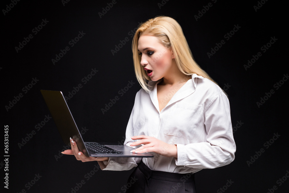 Studio portrait of blonde businesswoman in white blouse and black skirt holding laptop against dark background. Successful woman and stylish girl concept. Studio portrait of blonde businesswoman in white blouse and black skirt holding laptop against dark background. Successful woman and stylish girl concept.