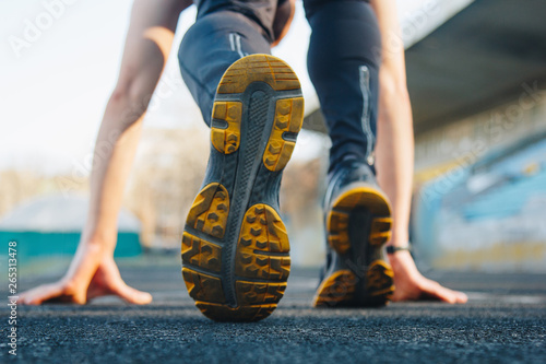 one man on the start line awaits the start of the sprint. stadium, rubber track. athletics competitions. Track and field runner in sport uniform at starting position. athlete, back view, close up