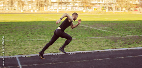 one caucasian male is doing a sprint start. running on the stadium on a rubber track. Track and field runner in sport uniform. energetic physical activities. outdoor exercise  healthy lifestyle