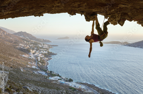 Young woman climbing in cave at sunset