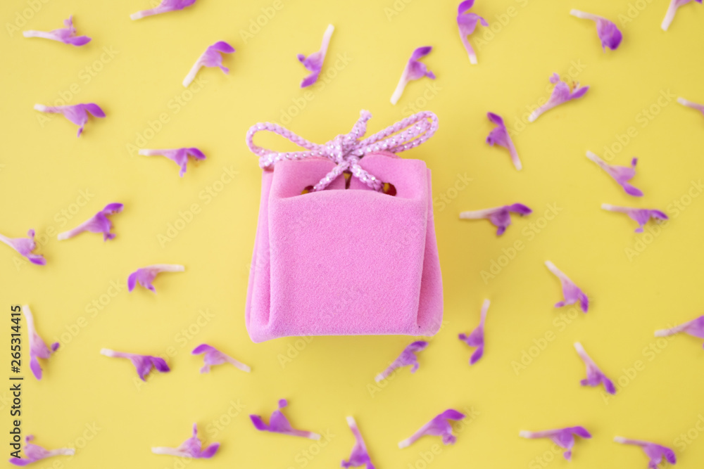 Pink gift box on a yellow background with flowers. Festive concept. Flat lay, top view Pink gift box on a yellow background with flowers. Festive concept. Flat lay, top view