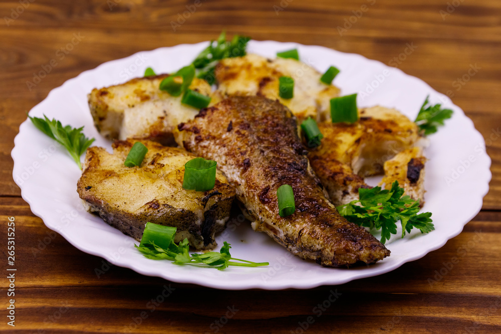 Roasted pollock in white plate on a wooden table