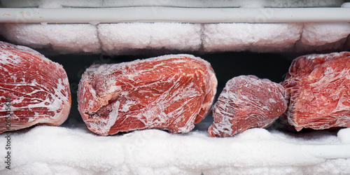 Obraz na plátne Large pieces of red meat in a freezer with a big quantity of frozen ice and snow