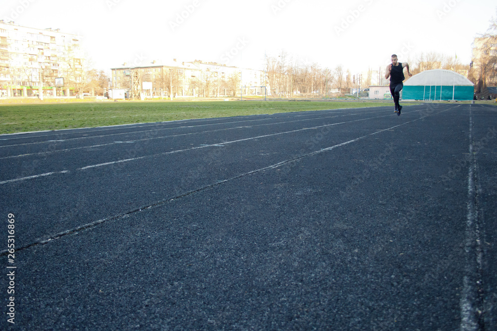 Obraz premium one caucasian male is doing a sprint start. running on the rubber track. Track and field runner in sport uniform. energetic physical activities. outdoor exercise, healthy lifestyle