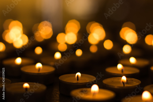 candles yellow fire illumination and unfocused bokeh effect background inside religion building in church service time twilight environment