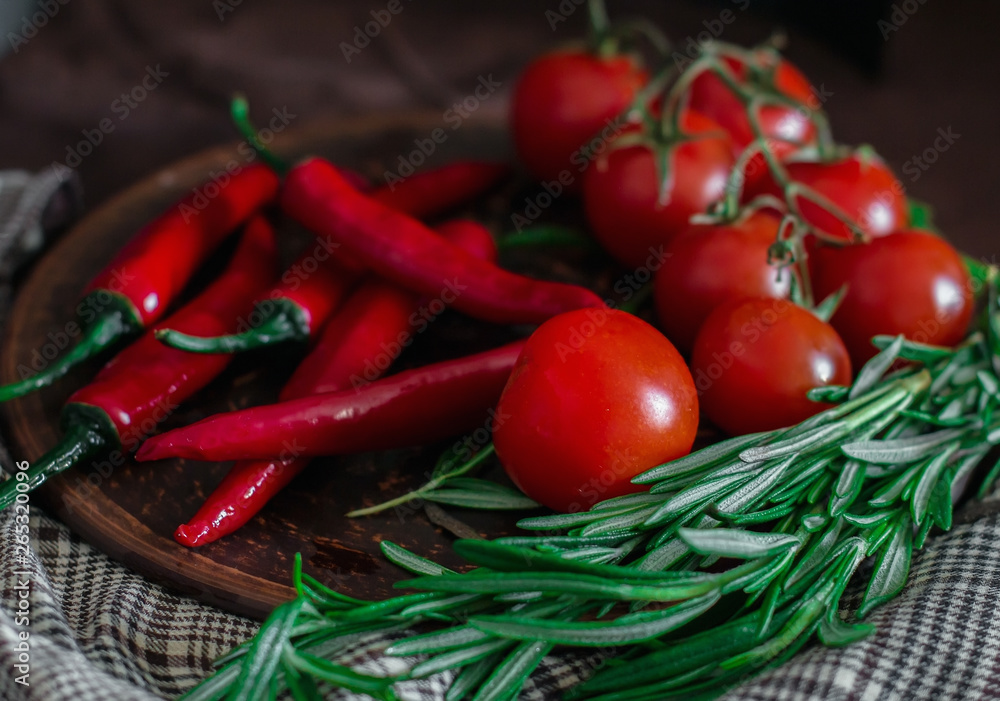 Fresh cherry tomatoes, sprigs of rosemary and chili peppers on a clay plate on the table. Fresh vegetables, herbs and spices - the concept of healthy eating. Food Photography Fresh cherry tomatoes, sprigs of rosemary and chili peppers on a clay plate on the table. Fresh vegetables, herbs and spices - the concept of healthy eating. Food Photography
