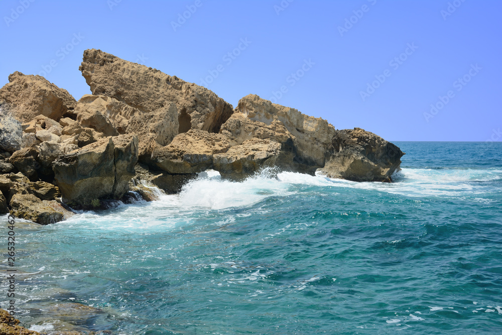 the waves running on the stony coast against the background of the blue sky