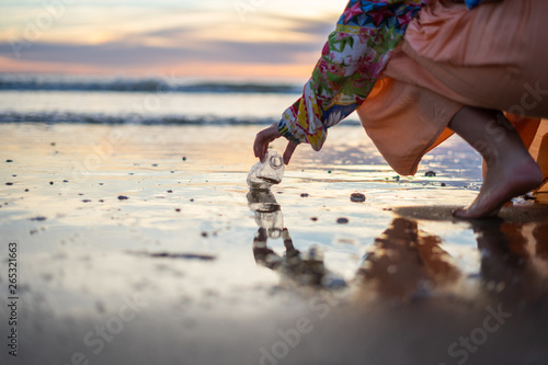 A woman cleaning a beach full of plastic bottles and rubbish in the sea