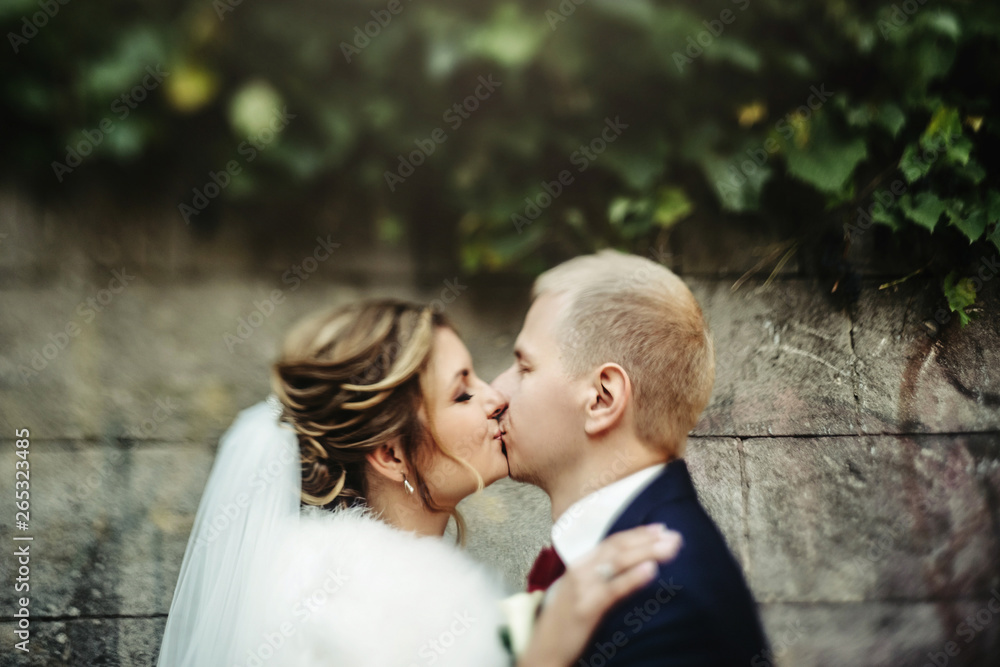 happy gorgeous blonde bride and stylish handsome groom with true emotions on background of old city wall happy gorgeous blonde bride and stylish handsome groom with true emotions on background of old city wall