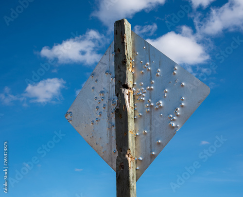 Fotografia Back of a caution road sign full of bullet holes