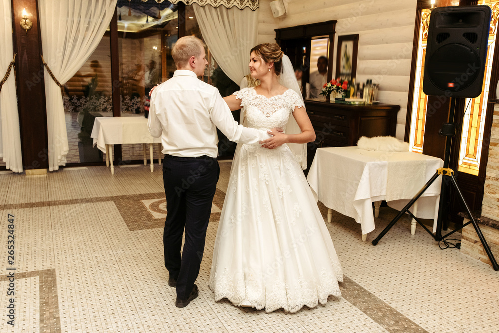 Fototapeta premium happy gorgeous bride and stylish groom dancing in rich restaurant with tender feelings, romantic moment