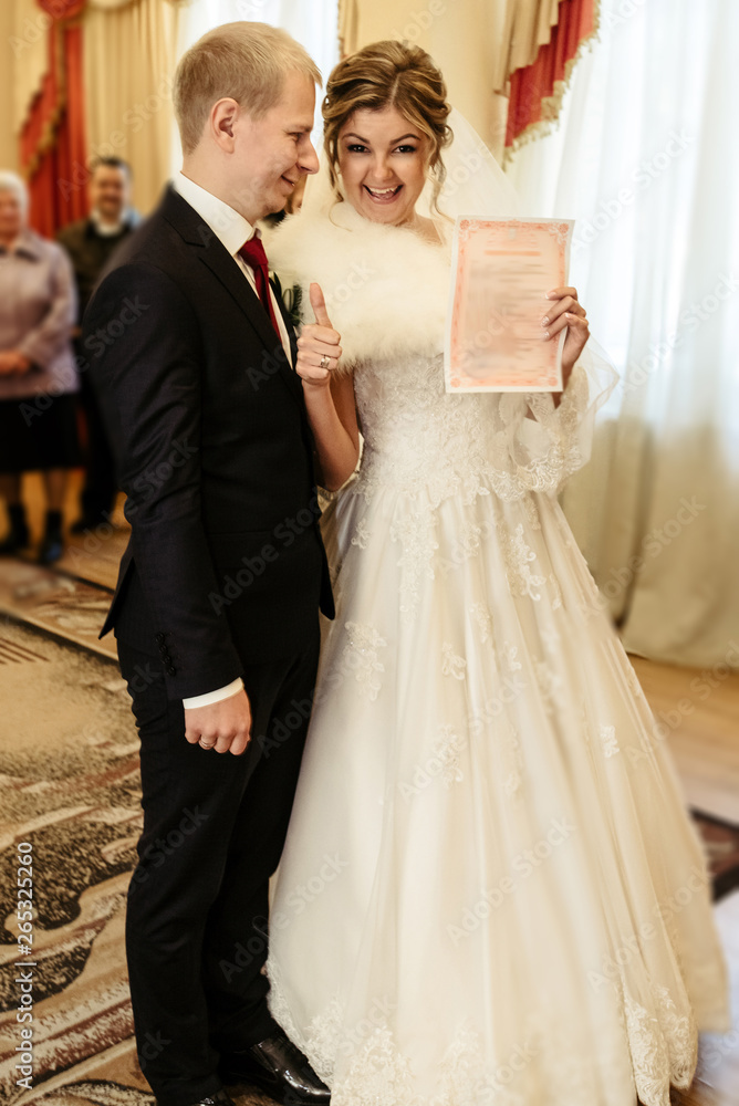 happy gorgeous bride and stylish groom holding official document wedding register, emotional moment, ceremony