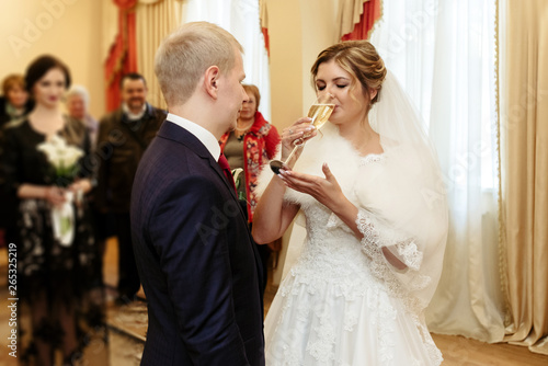 happy gorgeous bride and stylish groom drinking champagne, emotional moment, official ceremony