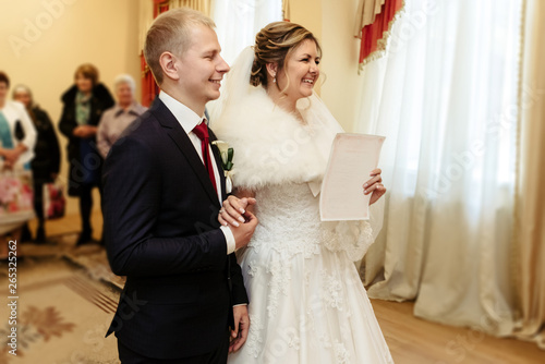 happy gorgeous bride and stylish groom holding official document wedding register, emotional moment, ceremony