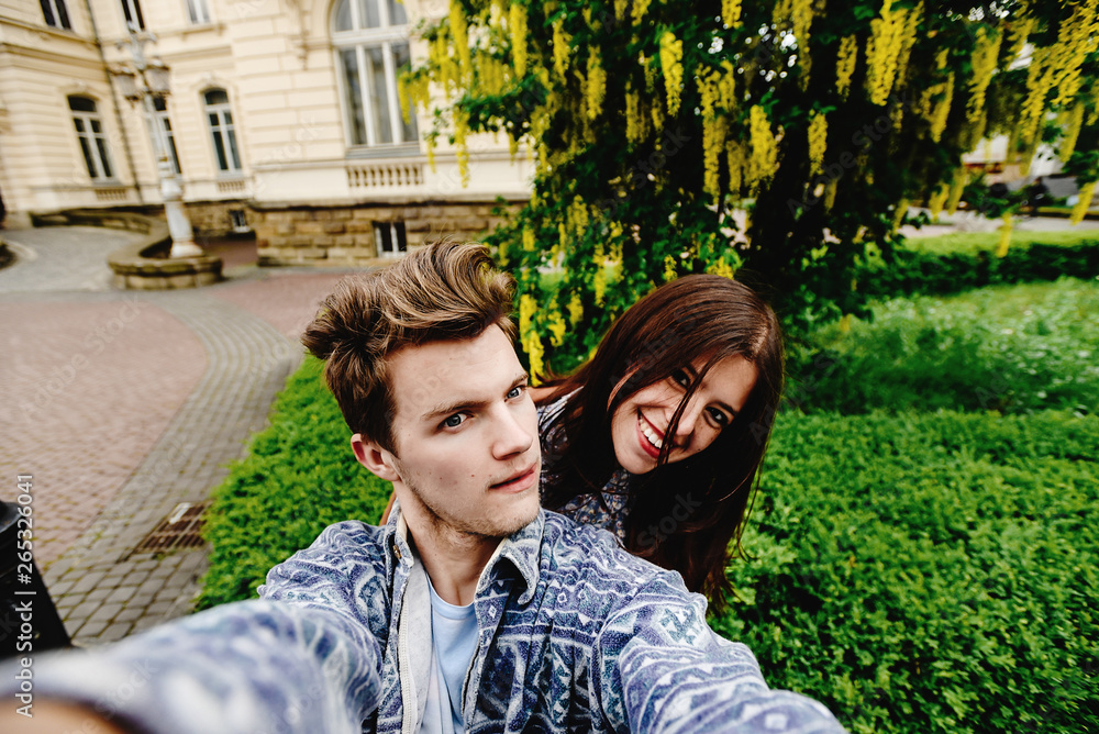 stylish happy hipster couple having fun traveling and taking selfies in the old city in europe in sunny spring time