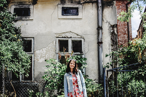 stylish brunette beautiful woman smiling in floral dress on the background of old building