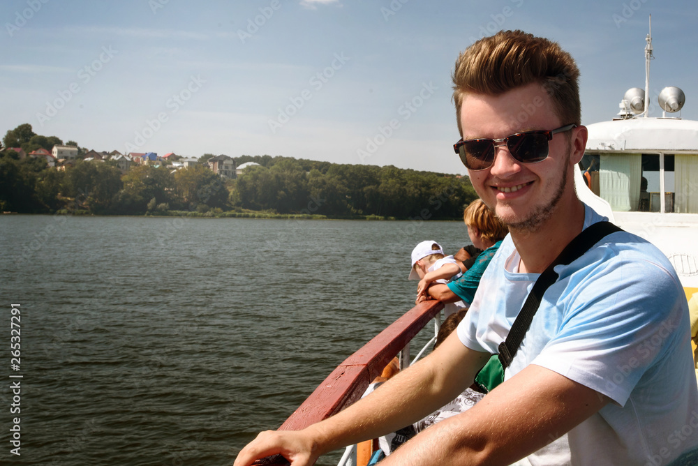 happy stylish hipster man sailing on a boat, having fun, summer vacation, space for text.