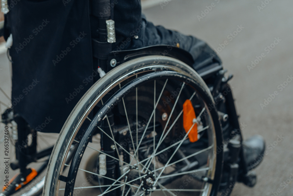 Close-up of male hand on wheel of wheelchair during walk in park Close-up of male hand on wheel of wheelchair during walk in park