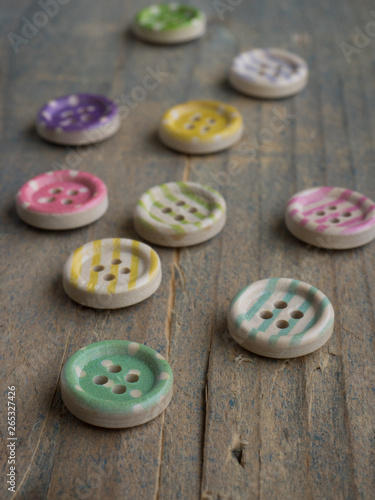 Wooden buttons with colorful stripes and colorful dots on a wooden background.