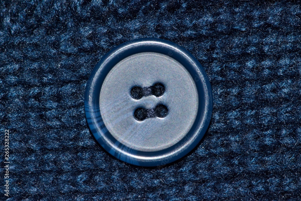 Blue Rag Button Navy blue macro swatch of a woolen garment with a blue button in the ...